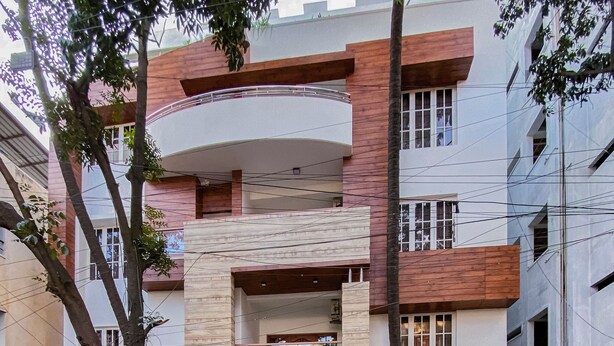 A modern multi-story building with a curved balcony, a gated entrance, and a visible sign reading "S.S. MANSION." - SS Mystic Apartotel (Bengaluru)