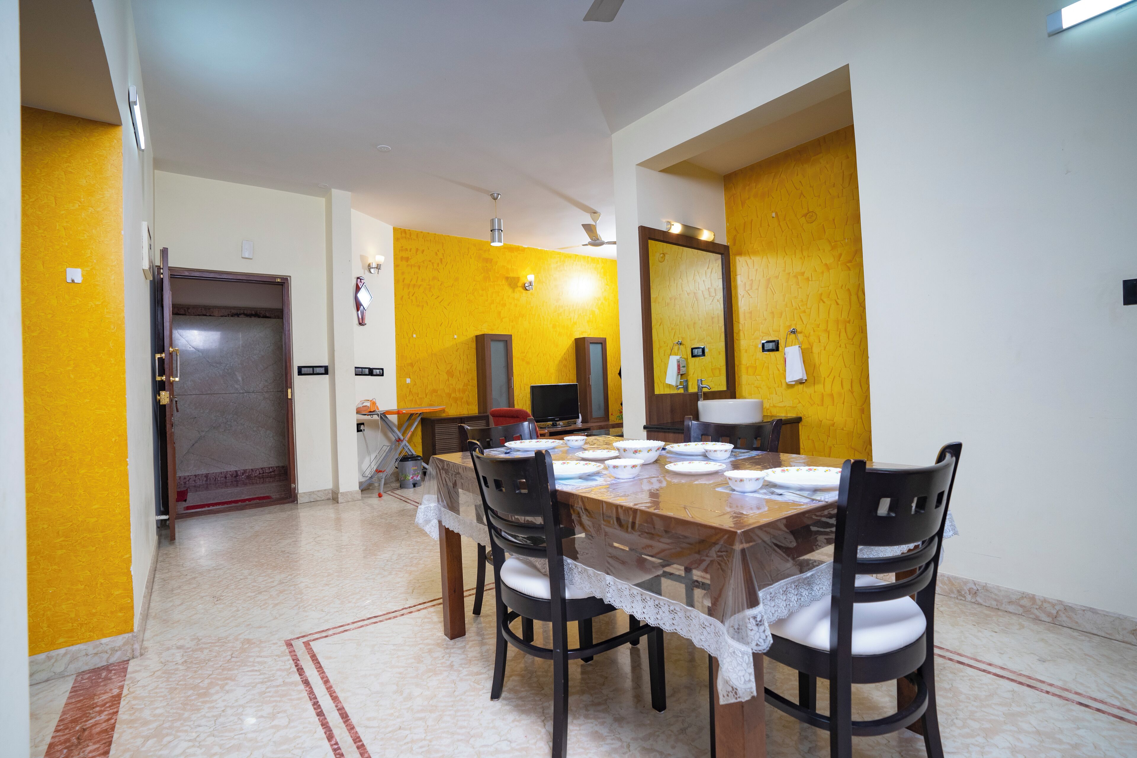 A dining area with a wooden table, chairs, and a yellow accent wall.