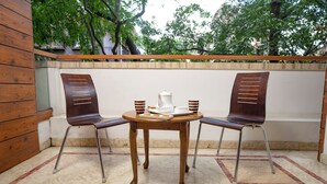 A small outdoor seating area with two wooden chairs and a table, featuring a white coffee pot and cups. - SS Mystic Apartotel (Bengaluru)