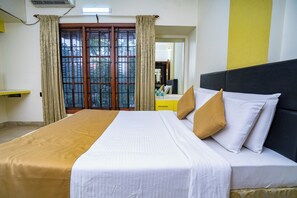 Una habitación de hotel con cama, escritorio y ventana con cortinas.