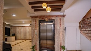An elevator entrance with marble walls, two potted plants, and a red carpet. - SS Mystic Apartotel (Bengaluru)