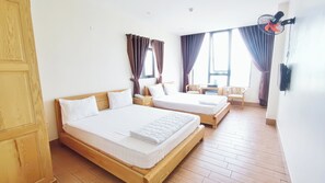A hotel room with two wooden beds, a small table, chairs, and a window with curtains. - Victory Hotel Da Nang - by Bay Luxury (Da Nang)