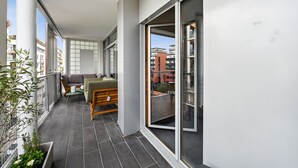 Ein Balkon mit einer Couch, einem kleinen Tisch und einem Blumentopf.