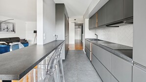 Eine moderne Küche mit grauen Schränken, einer schwarzen Arbeitsplatte und einer gefliesten Spritzschutzwand.