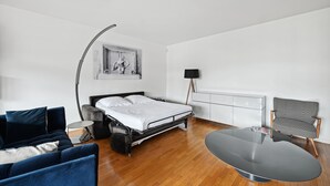 Ein modernes Hotelzimmer mit Bett, einer Couch, einem Sessel, einem Schreibtisch und einer Lampe.
