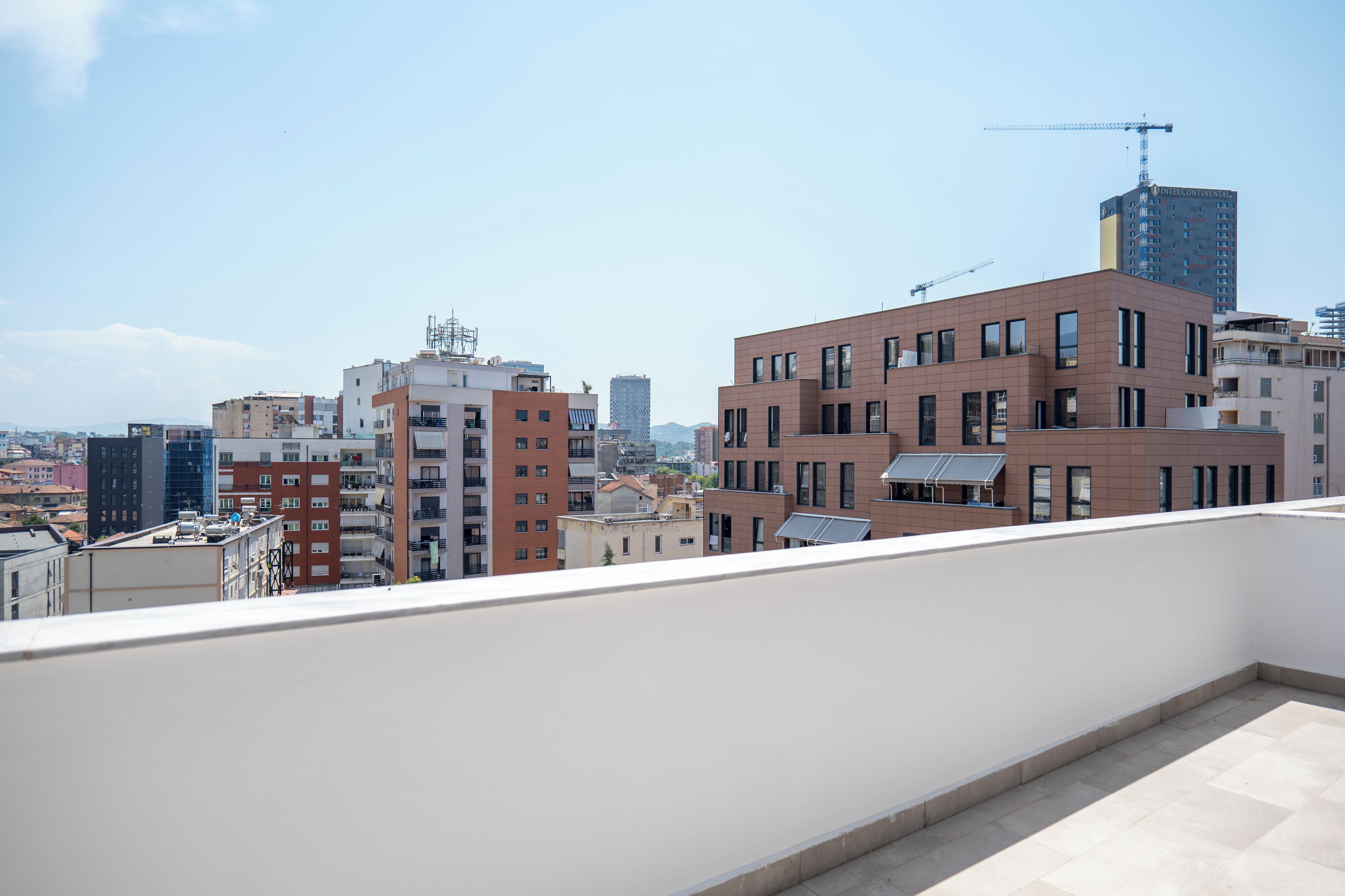 Un paysage urbain avec des bâtiments modernes, dont un imposant bâtiment en briques rouges doté de nombreuses fenêtres et d’un toit plat.