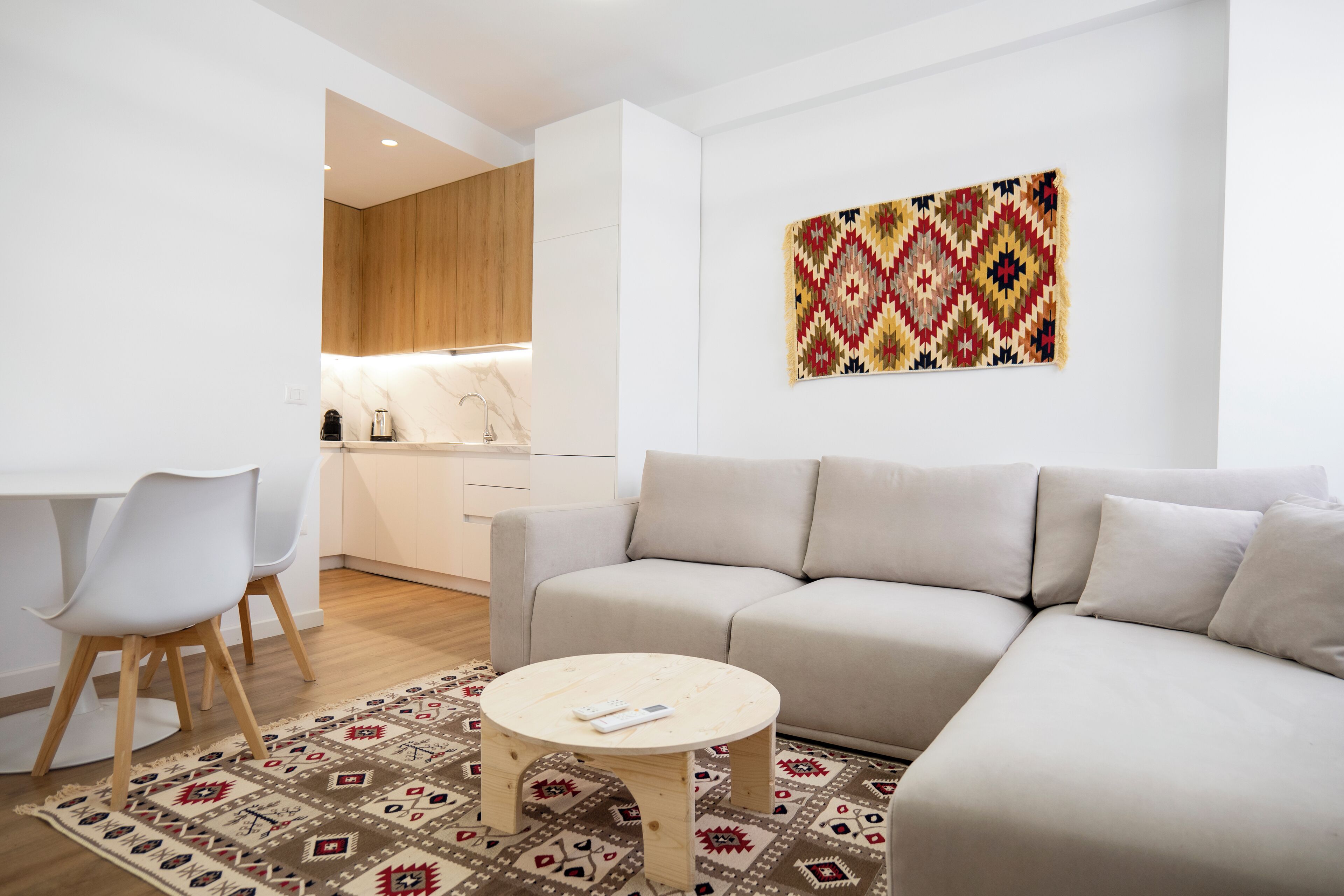 A modern living room with a beige sofa, a round coffee table, and a patterned rug.