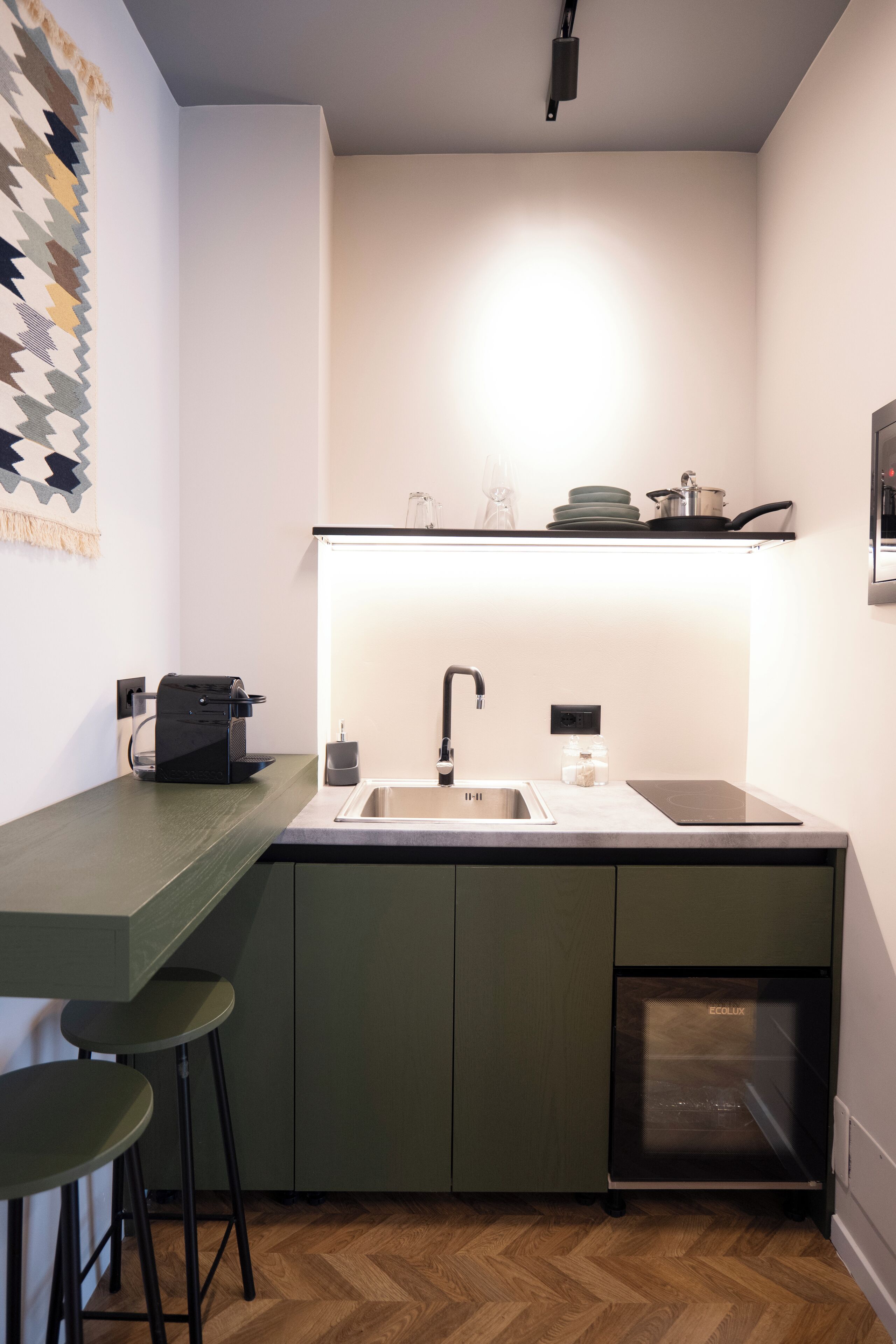 Une cuisine compacte équipée d’un lave-vaisselle intégré, d’une machine à café et d’un évier.
