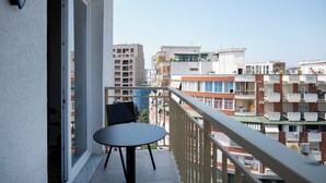A balcony with a table and chairs, overlooking a residential area with multiple buildings. - Muz Studios (Tirana)