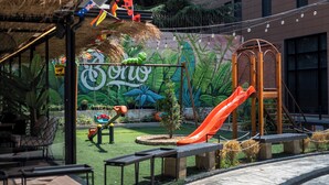 A playground with a slide, swings, and a climbing structure. - Muz Studios (Tirana)