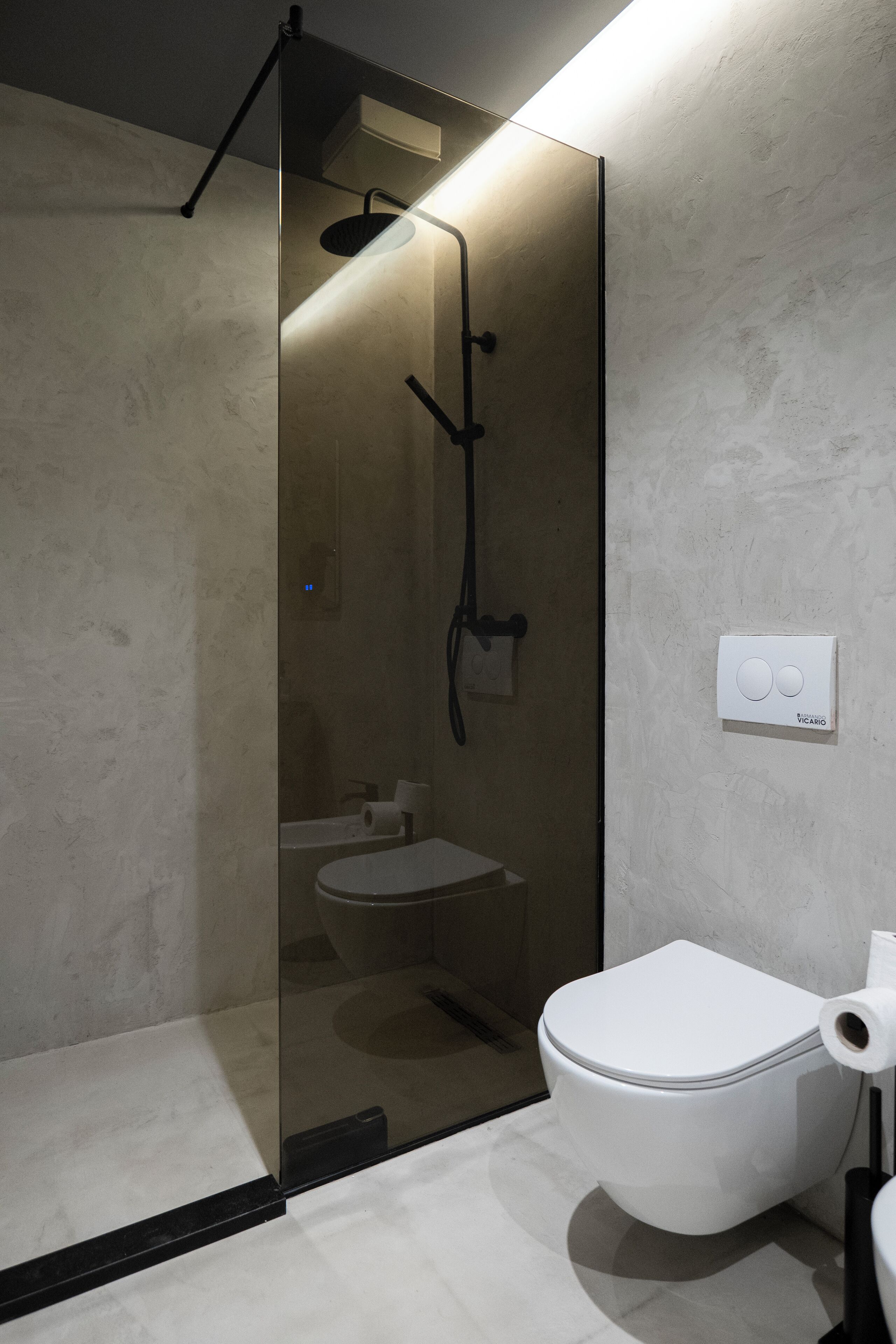 Un bagno moderno con doccia vetrata, un water bianco e un lavandino.