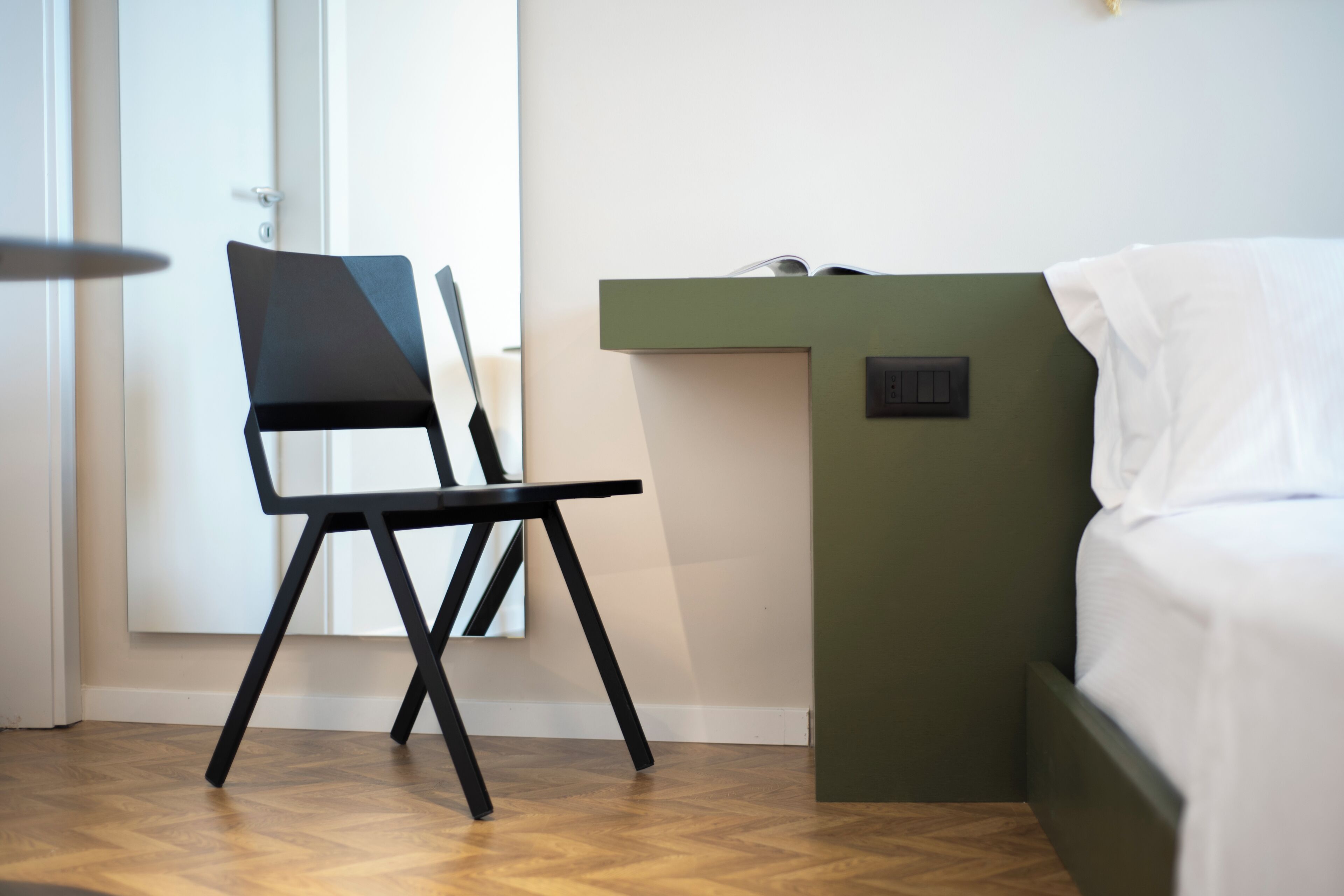 Een kamer met een bed, een stoel, een bureau en een deur.