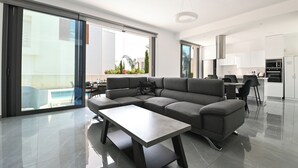 Ein modernes Wohnzimmer mit einem Ecksofa, einem Esstisch und einer Küchenzeile.