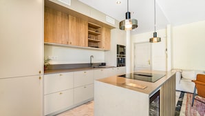 A modern kitchen with white cabinetry, a central island, and pendant lighting. - Hacienda Nagueles (Marbella)