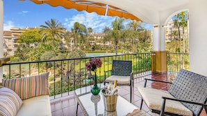 A balcony with a view of a well-maintained garden and buildings in the background. - Hacienda Nagueles (Marbella)