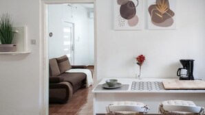 Uma sala de estar moderna com um sofá, uma mesa de jantar com um vaso de flores e uma cafeteira.