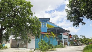 A hotel with a prominent 'PPI Inn' sign, a covered outdoor area, and a street view with parked vehicles. - Hotel O Papi Inn Guesthouse (Palangkaraya)