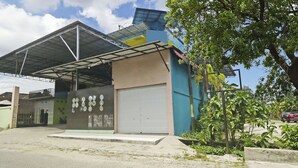 A building with a covered entrance, a garage door, and a wall with various signs and posters. - Hotel O Papi Inn Guesthouse (Palangkaraya)