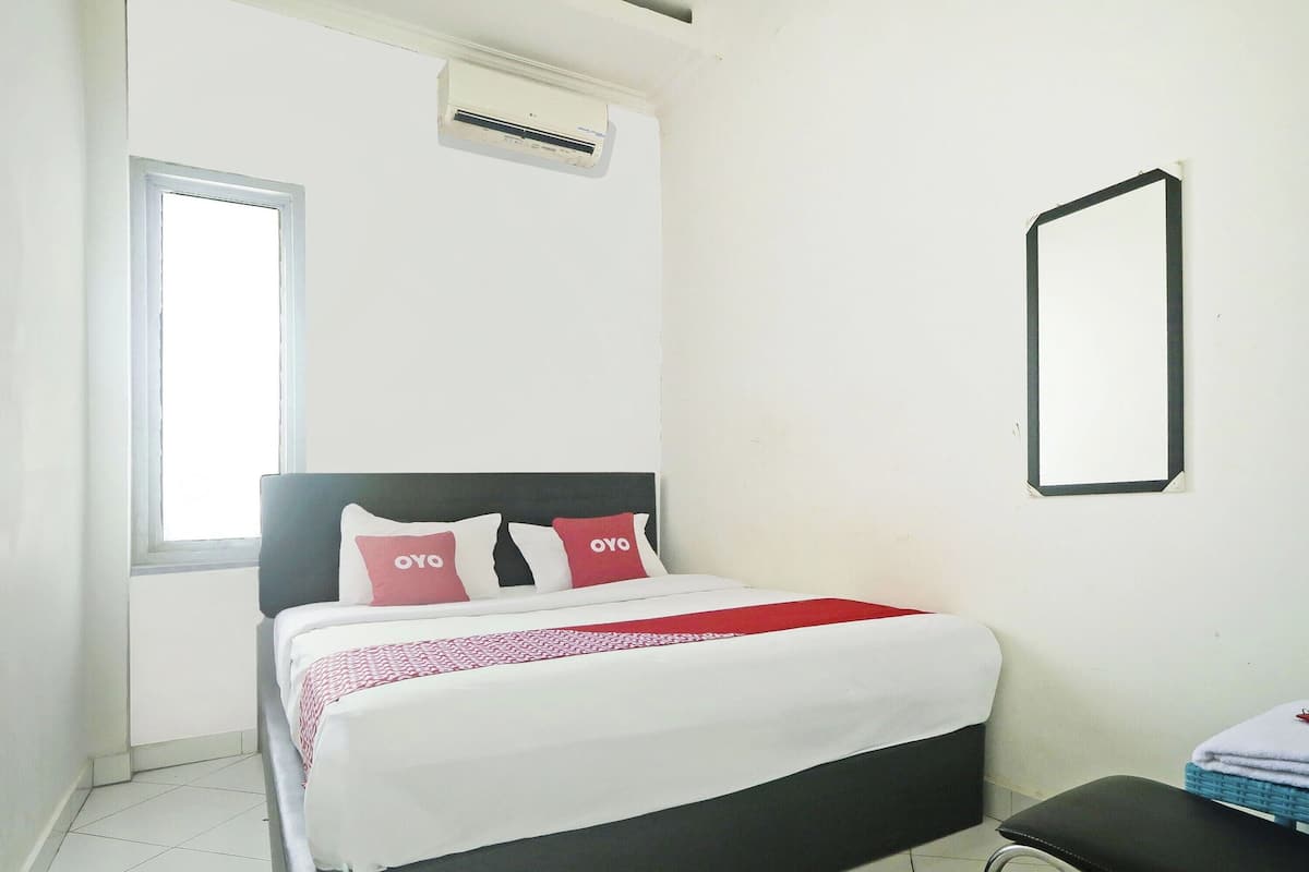 A bedroom with a bed, pillows, a bedside table, and a window.