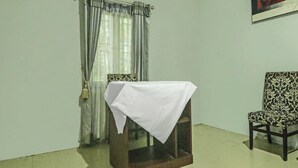 A room with a table covered by a white cloth, a patterned chair, and a curtain with a tassel. - Hotel O Papi Inn Guesthouse (Palangkaraya)