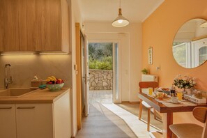 Une cuisine avec des meubles de rangement en bois, un saladier rempli de fruits et une table à manger avec des chaises.