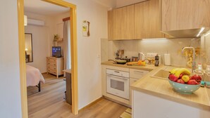 Eine kleine Küche mit Holzschränken, einem Spülbecken und einer Arbeitsplatte mit Obstschüssel.