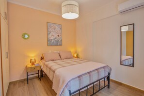 Une chambre à coucher avec un lit, des lampes de chevet, un miroir fixé au mur et un luminaire au plafond.