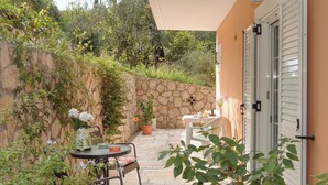 Eine Terrasse mit Steinmauer, Tisch und Stühlen sowie einem Blumentopf.