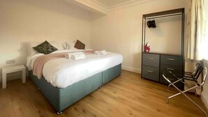Ein Schlafzimmer mit einem Bett, einem Nachttisch, einer Kommode, einem Sessel und einem Spiegel.