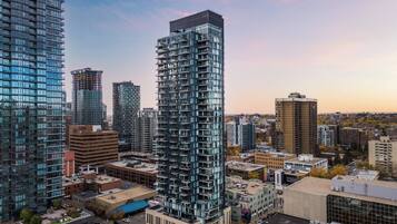 A high-rise building with a modern glass facade, surrounded by other buildings and a clear sky.