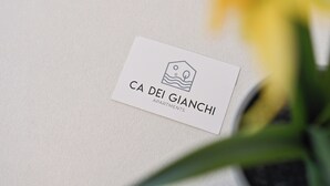 Een visitekaartje voor 'CA DEI GIANCHI APARTMENTS' met een eenvoudig logo en tekst.