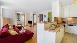 A modern living room with a red sofa, a kitchen with white cabinets, and a dining area with a table and chairs. - Casa Nova Bella With Free Parking (Lugano)