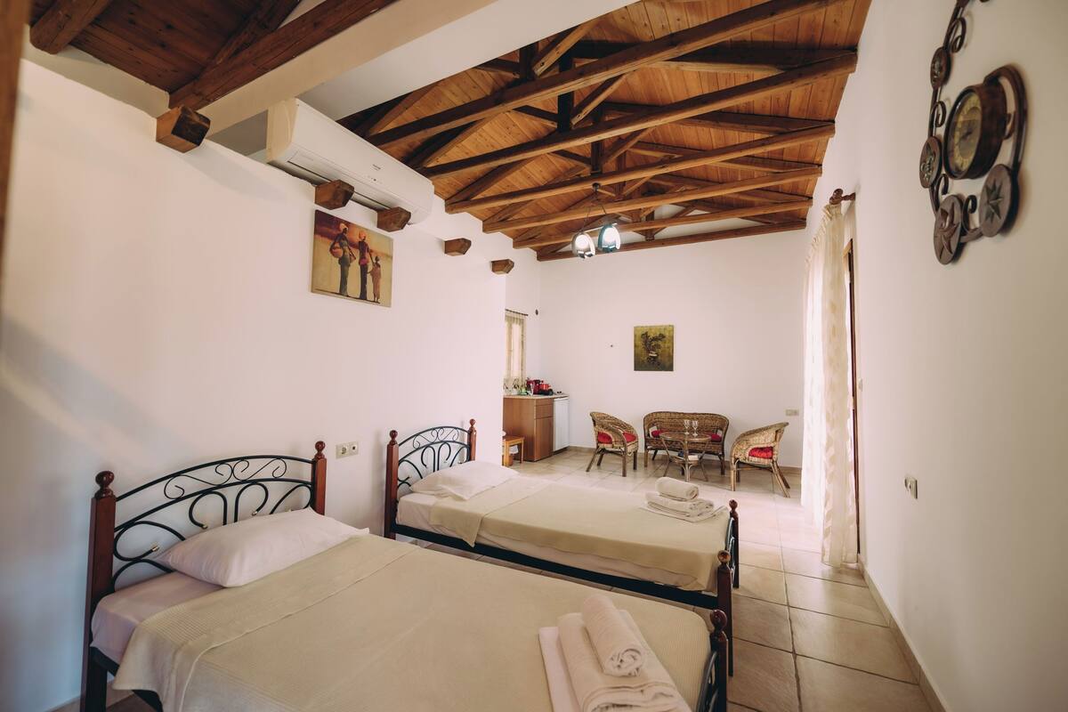 Une chambre avec deux lits, un plafond en bois, un coin repas avec des chaises et une petite table.