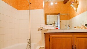 A bathroom with a bathtub, a wooden vanity, and a mirror. - Bel Appartement T1bis de Caractère Jardin Royal. Quartier des Carmes (Toulouse)