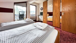 A hotel room with two beds, a large window, a mirror, and a wardrobe. - Calendula vacation apartment (Oberstaufen)