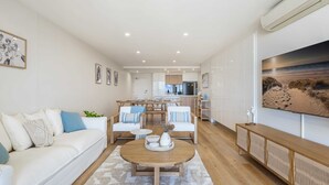 Una sala de estar moderna con un sofá, una mesa de centro y un comedor al fondo.