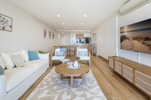 Una sala de estar moderna con un sofá, una mesa de centro y un comedor al fondo.