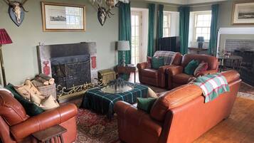 A traditional living room with leather sofas, a fireplace, and decorative antlers on the wall.