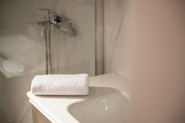 Une serviette blanche sur le lavabo d’une salle de bain.