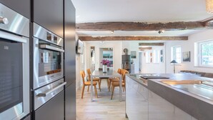 Una cocina moderna con electrodomésticos de acero inoxidable, una mesa de comedor de madera con sillas y una isla grande con tabla de cortar.