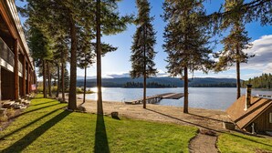 Una proprietà sul lago con terrazza in legno, vialetto in pietra e vista sul lago e sulle montagne.
