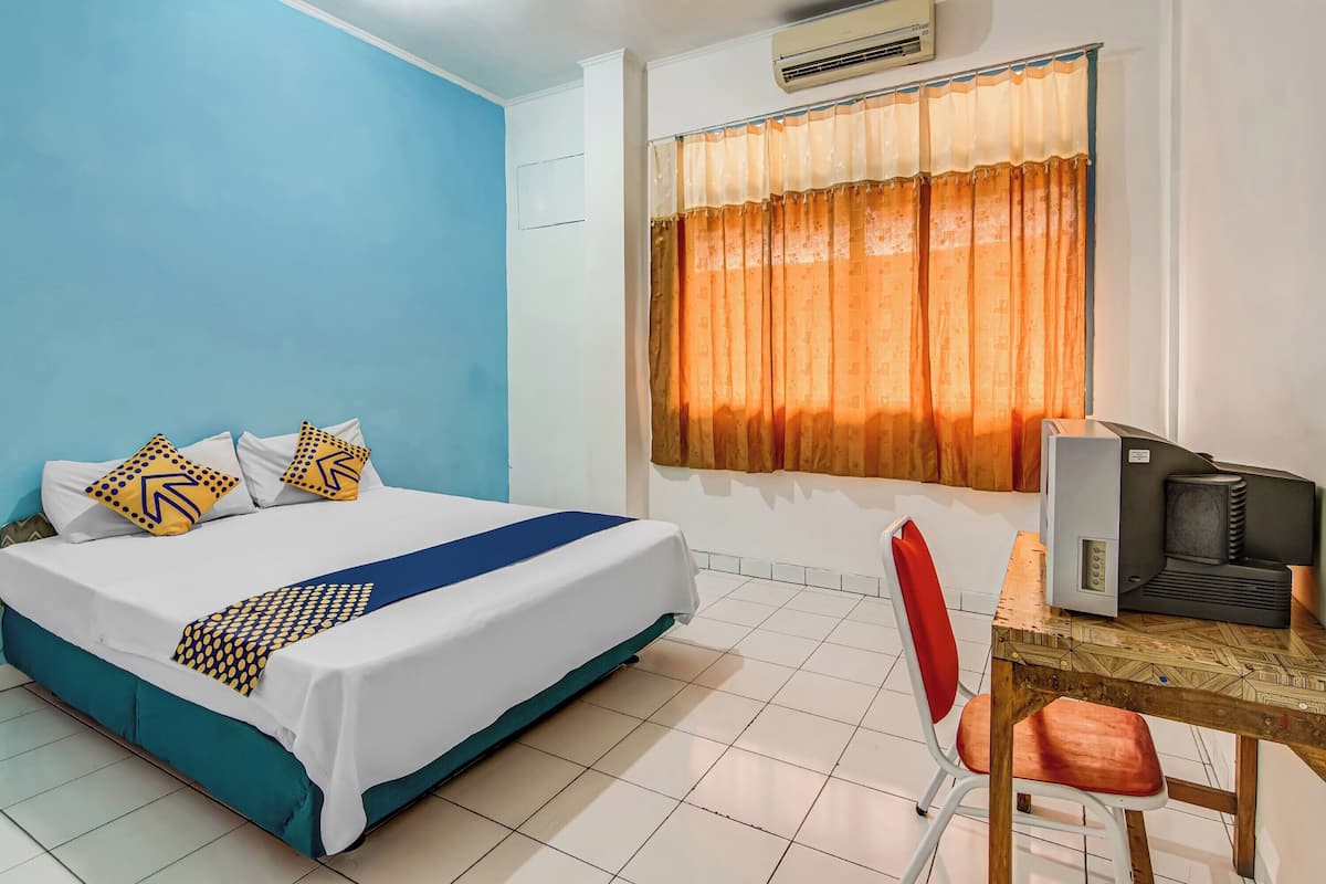 Een hotelkamer met een bed, een bureau met een computer en een raam met gordijnen.