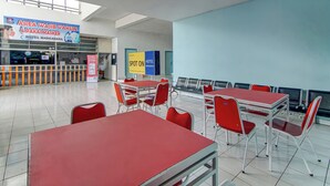 Rebedor d'hotel amb taules i cadires vermelles, una taula de recepció i senyals que indiquen mesures de seguretat relacionades amb la COVID-19.
