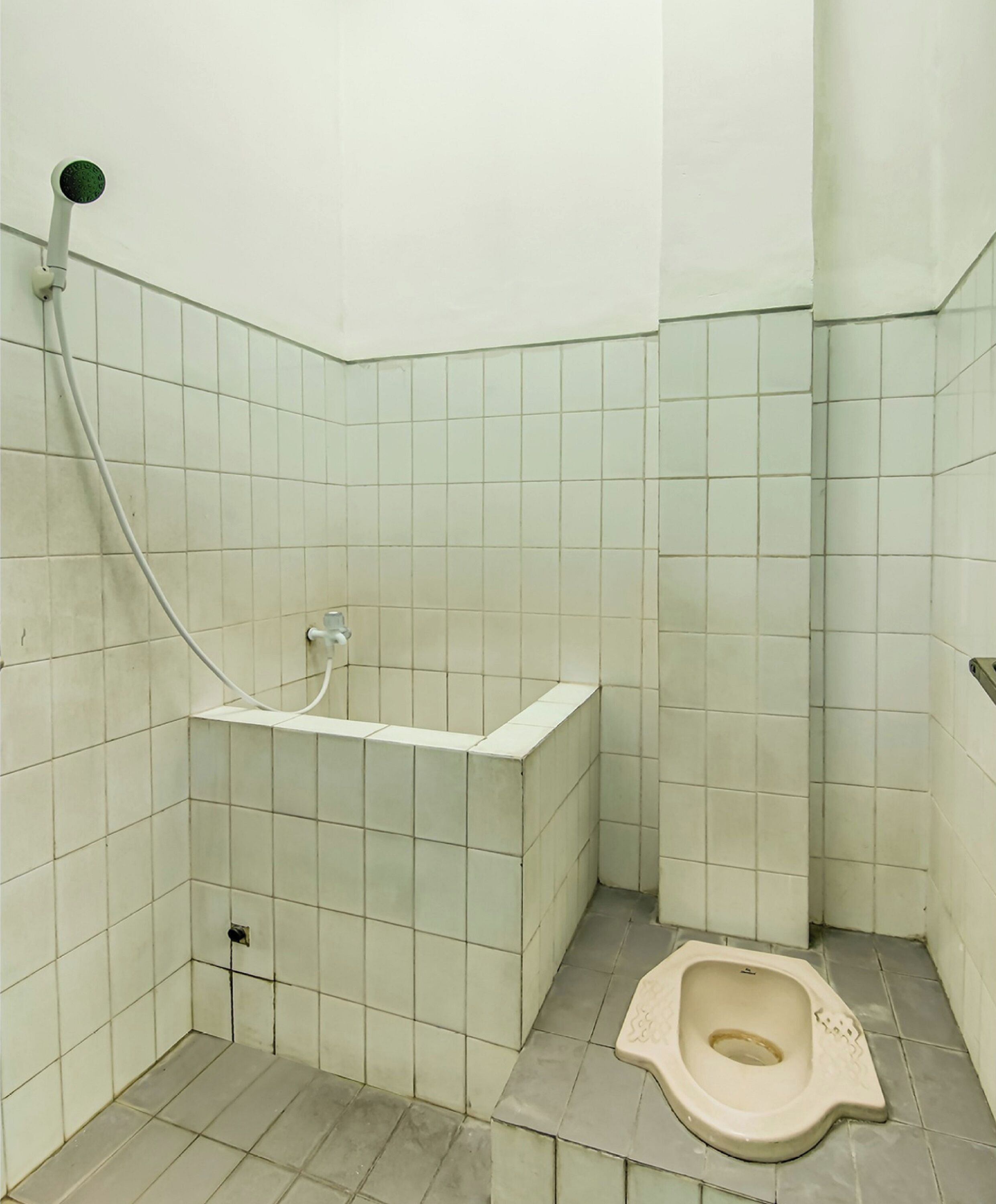 A small, tiled bathroom with a toilet, a shower, and a sink.