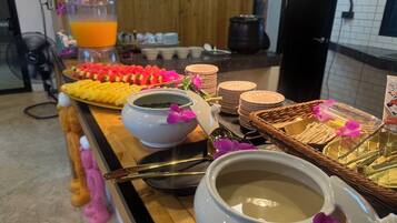 Ein Buffet mit verschiedenen Speisen, darunter Obst, Gebäck und eine Suppenschüssel.
