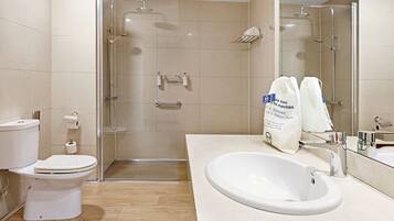 Un baño moderno con inodoro, lavamanos y cabina de ducha con mampara de cristal.