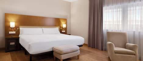 Una habitación de hotel con una cama grande, lámparas de noche, una silla y un ventanal con cortinas.
