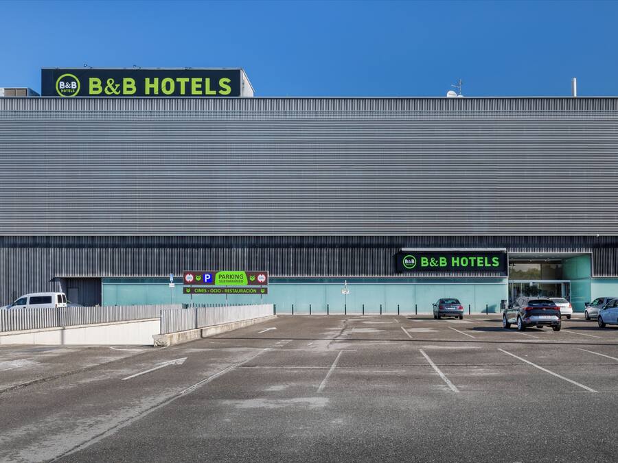 Un hotel B&B con un amplio estacionamiento y un letrero que indica servicios como cine, restaurante y estacionamiento.