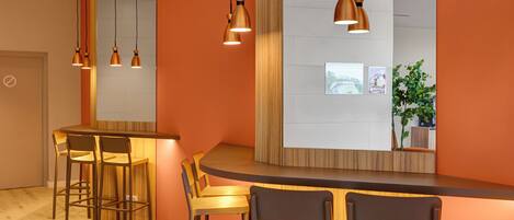 A modern bar area with wooden chairs and pendant lighting.