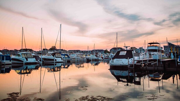 Una marina con varios barcos amarrados en aguas tranquilas que reflejan el cielo.